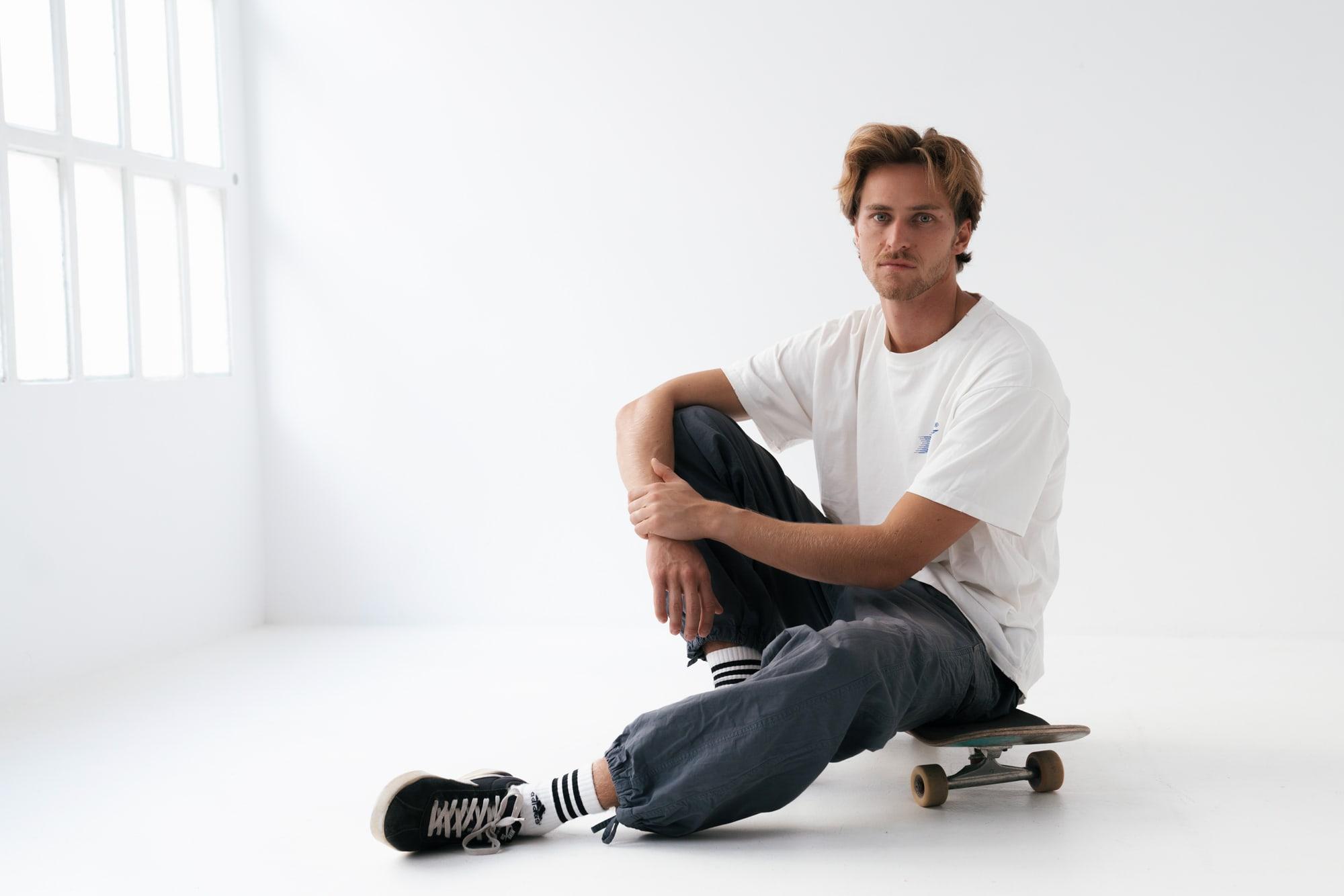 Tekke Voorham, sitting on a skateboard in a white studio